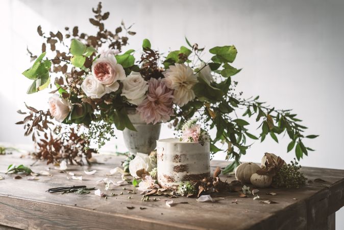 plate with cake decorated flower on table with bouquet of blooms in vase