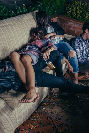 Young drunk friends sleeping on a sofa after a party