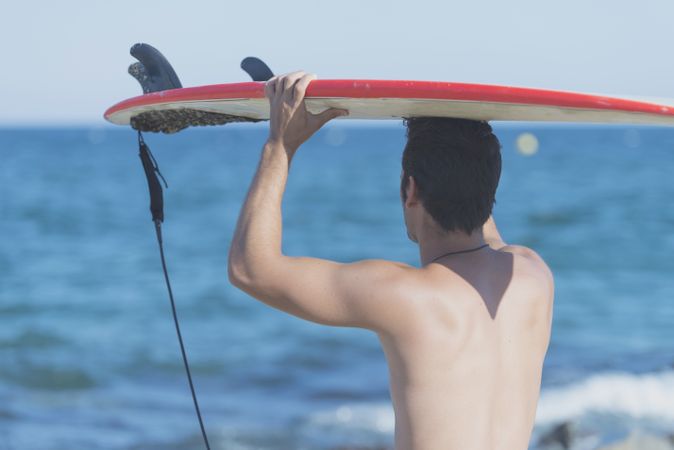 Male surfer looking out to the ocean with board on head
