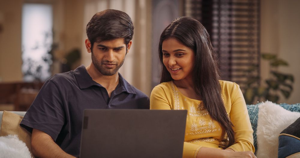Smiling Indian Couple Using Laptop Computer at Home to do Online Shopping Together, Searching For Perfect Gifts