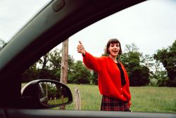 Woman in red sweater catching car on road