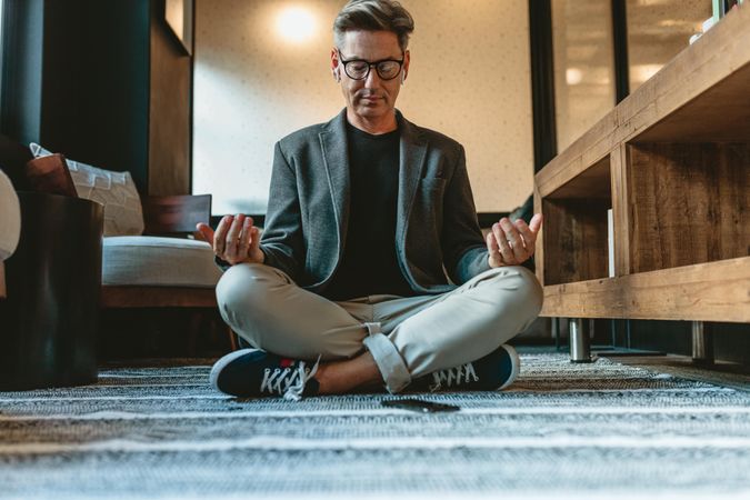 Businessman sitting on floor and meditating in yoga pose