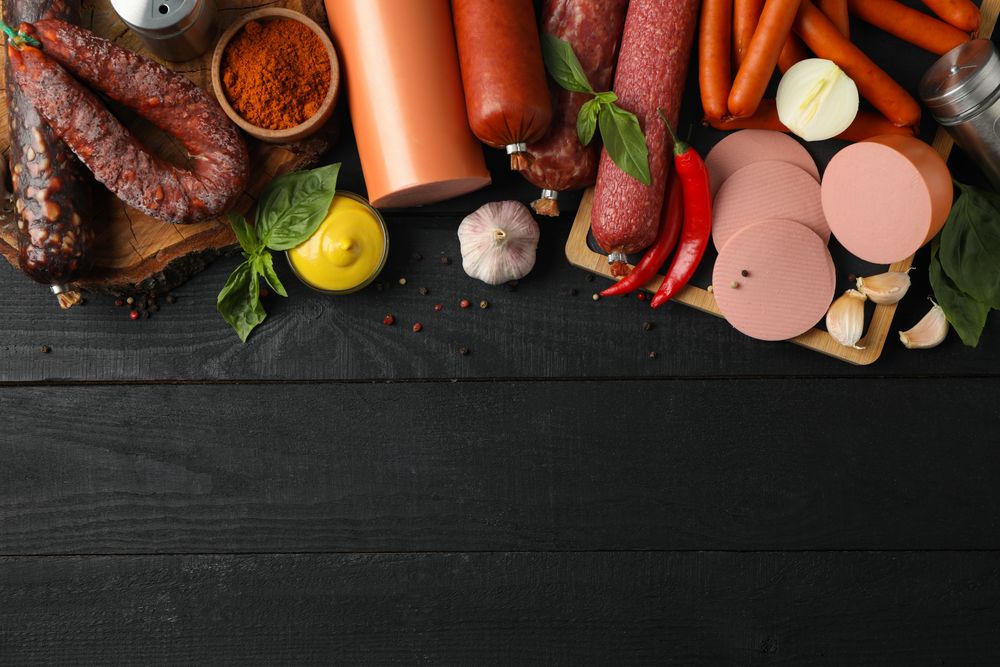 Looking down at variety of cured meats with mustard, garlic and peppers