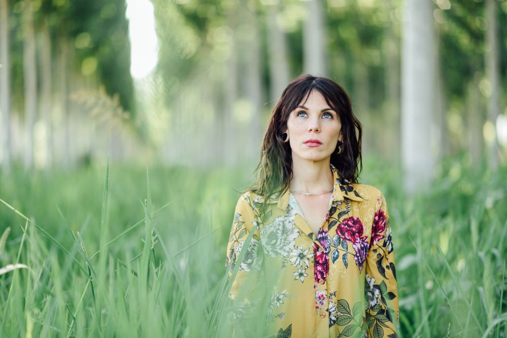 Serious brunette female looking up in field of tall grass