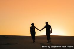 Silhouette of man and woman holding hands standing on sand during sunset 0PWdeb