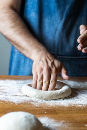 Crop man flattening dough for pizza
