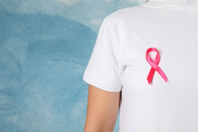 Person in t-shirt with awareness ribbon against blue background