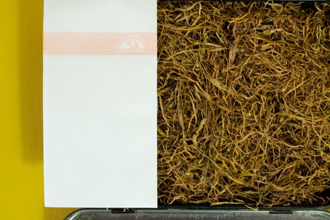 Close up top view of loose leaf tobacco with rolling papers