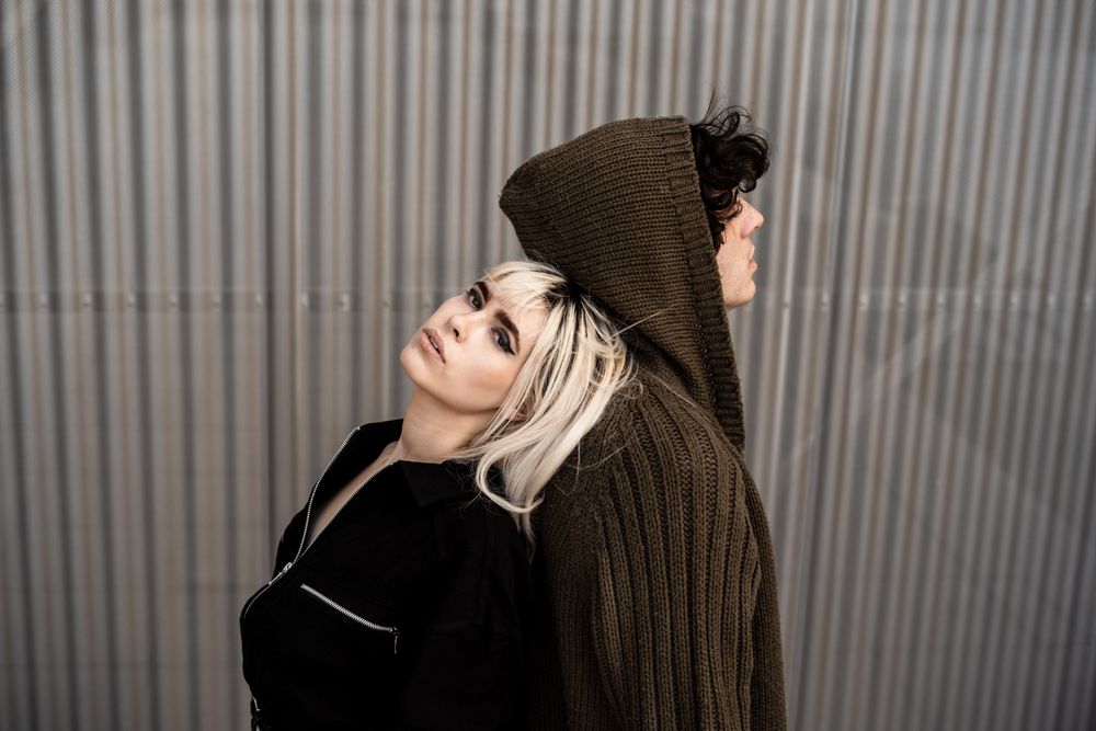 Loving man and woman supporting each other while standing back to back