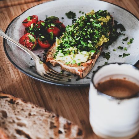 Avocado toast on sourdough bread, with cherry tomatoes and coffee, square crop