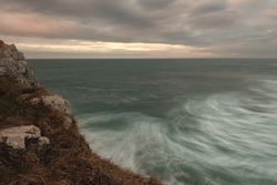 Powerful wave splashing at granite cliff