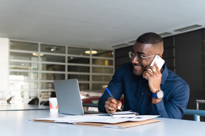 Black man talking on phone near laptop in office