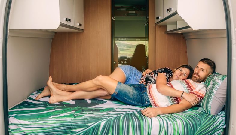 Male and female cuddling on bed in motorhome