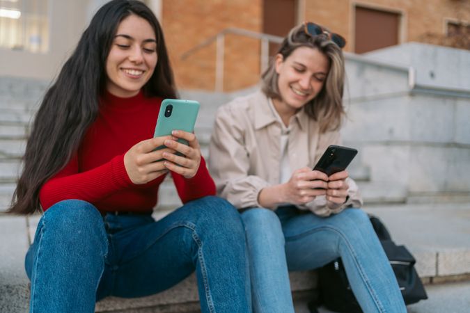 two student sitting on the stairs watching the mobile