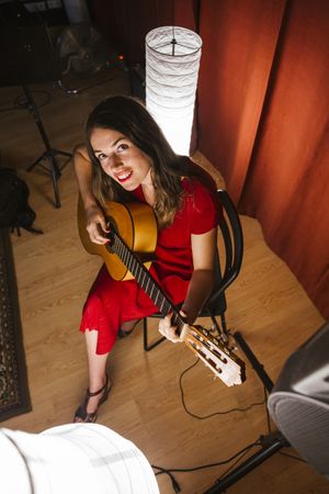 Woman singing and playing guitar on stage in lamplight