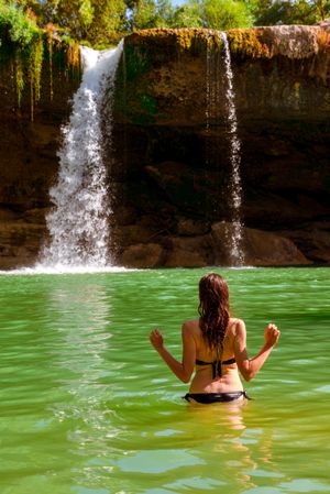 Anonymous female standing near amazing waterfall