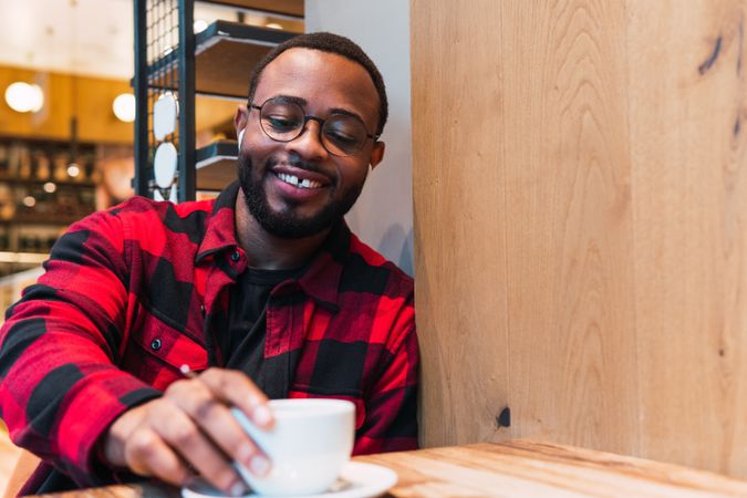 Smiling Black man with cup of coffee in cafe