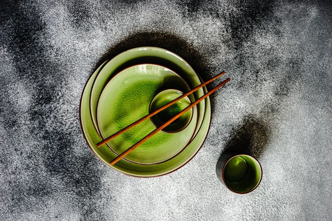 Green plates and chopsticks on grey background