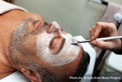 Cropped image of person applying cream on man's face 5kK1W5