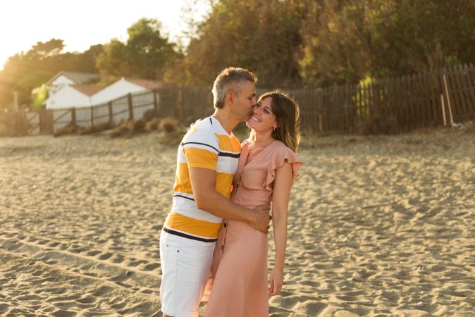 Laughing couple hugging on sandy beach