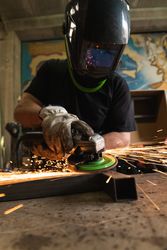 Male worker using electric grinder in workshop