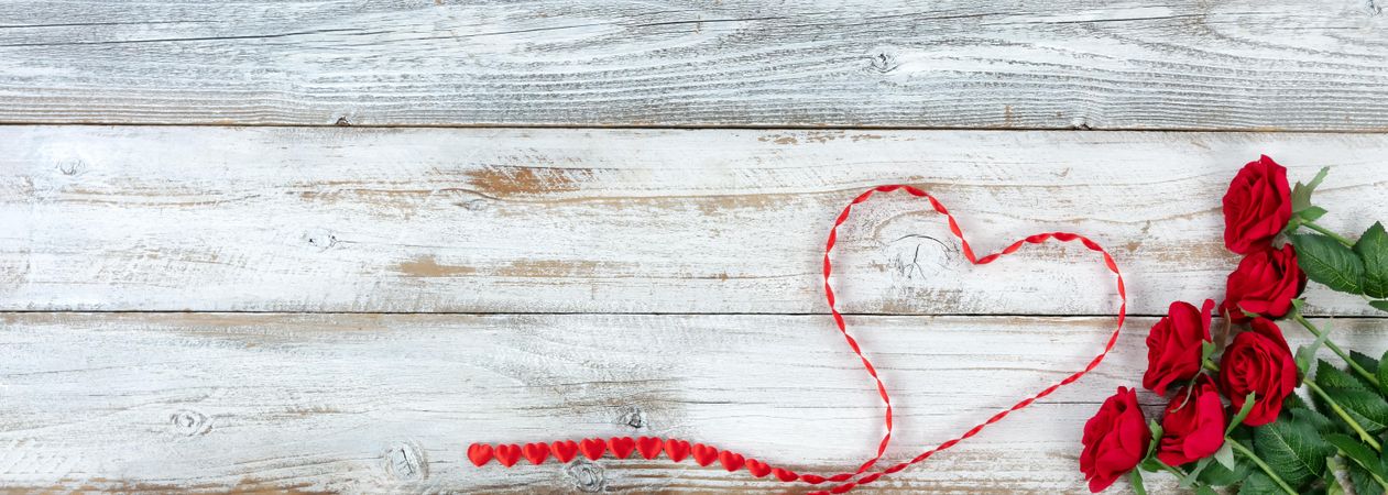 Romantic red roses and heart shaped ribbon on rustic wood