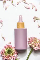 Pastel purple cosmetic bottle with pipette with pink flowers