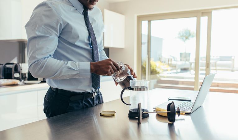 Businessman preparing coffee while doing office work at home