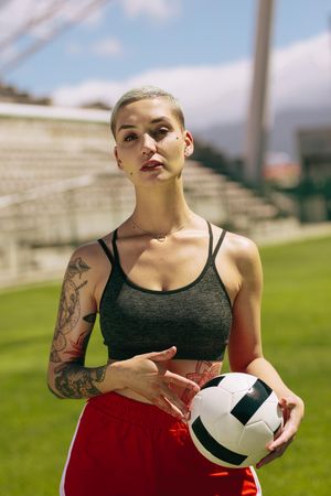 Portrait of female football player holding a ball on football field