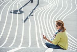 Modern relaxed woman on marked road and browsing smartphone