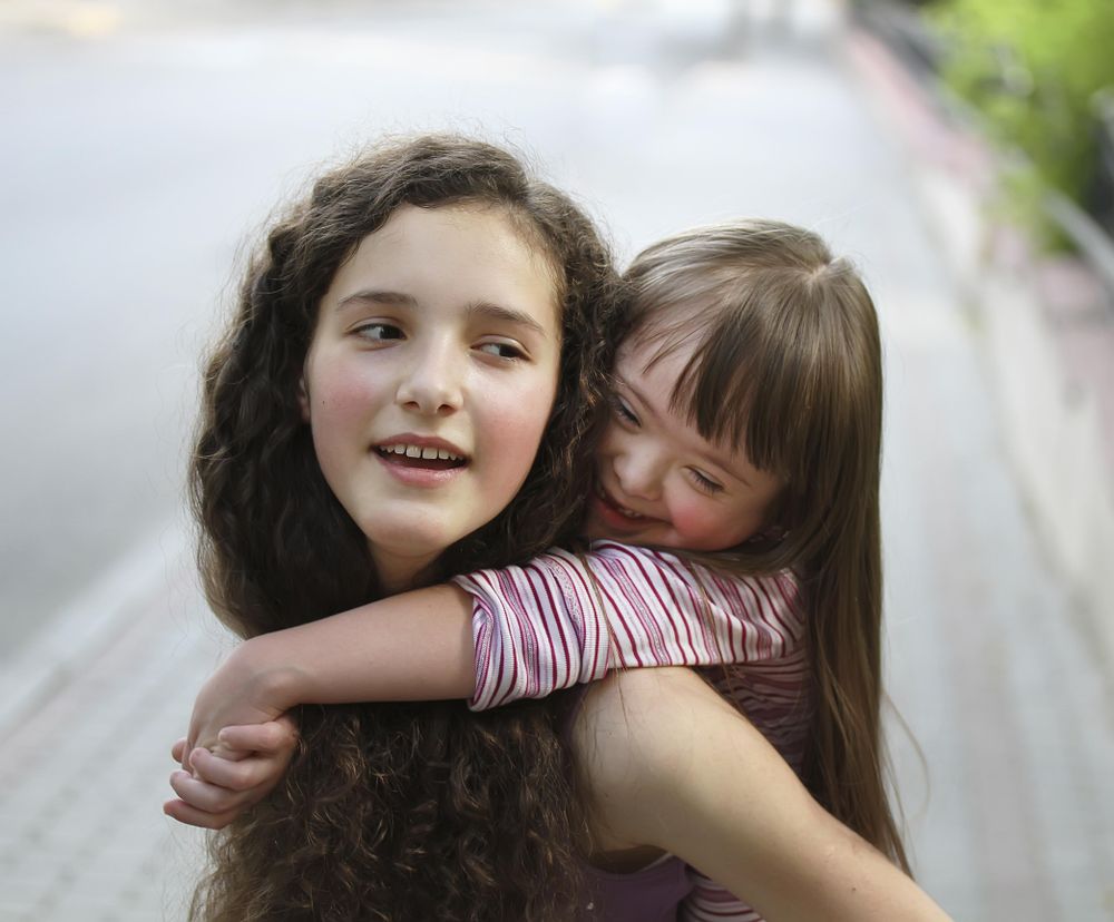 Young girl carrying sister giving piggyback ride Stock Photo