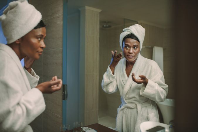 Woman applying cream in bathroom mirror after her bath