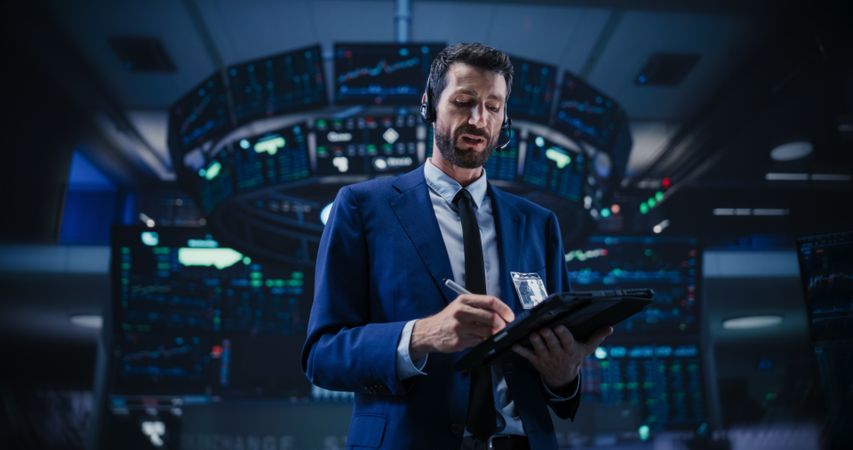 Productive Stock Exchange Broker Working on a Tablet Computer, Manipulating Company Shares, Valuable Technology Investments, Public and Private Securities.
