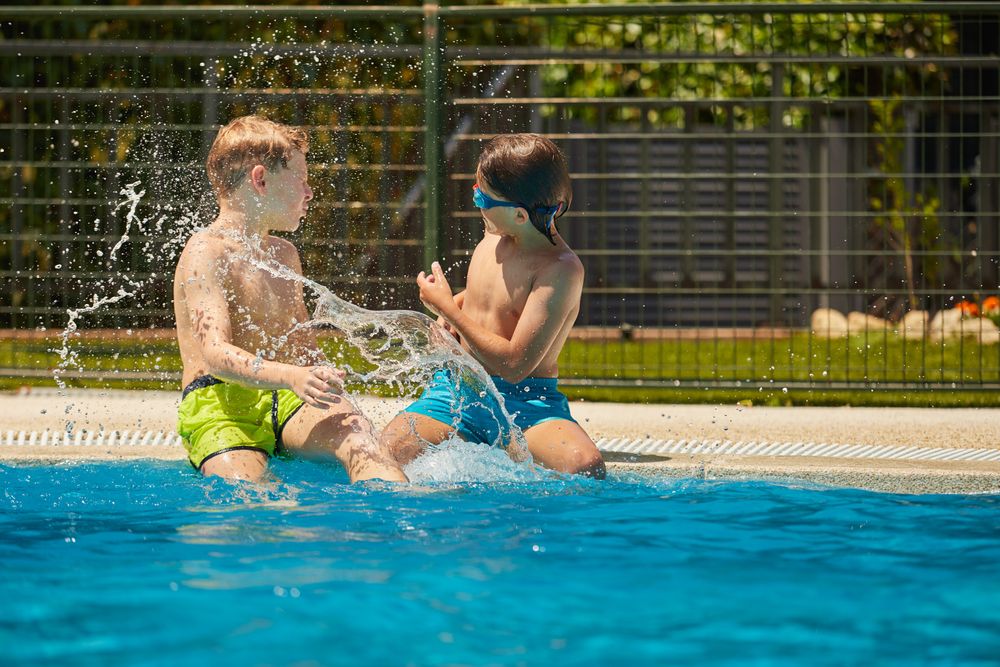 Cheerful boys playing with water in swimming pool