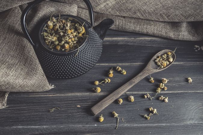 Spoonful of dried chamomile on wooden table