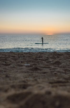 Man practicing paddle surfing with neoprene in a sunrise