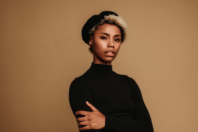 Portrait of Black woman in cap against brown background