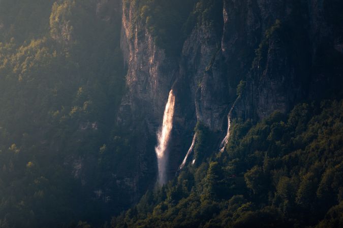 Majestic mountain waterfall on side of rock in sunny day
