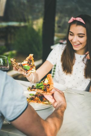 Couple eating pizza al fresco with wine with woman smiling