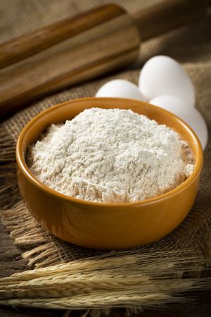 Bowl with wheat flour on the table.