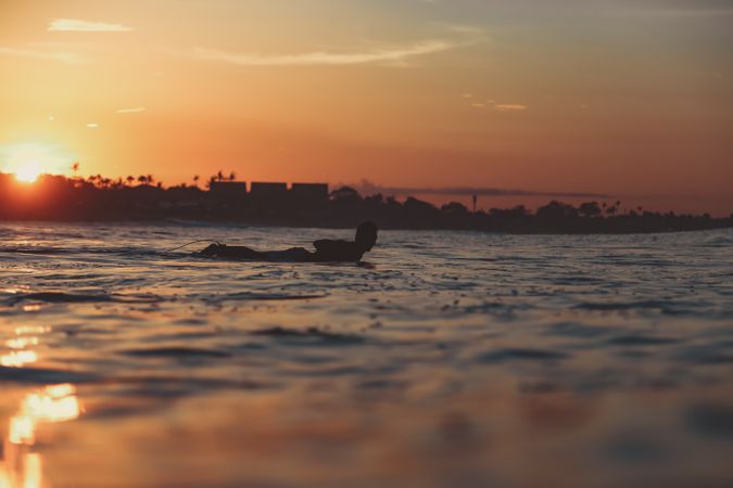 Man on surf board on waving water at sunset