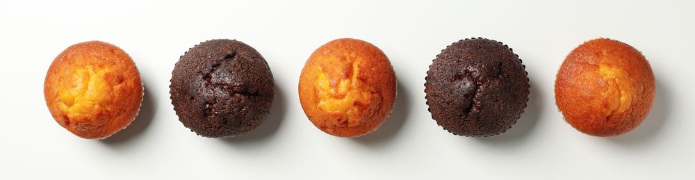 Flat lay with tasty muffins on light background, top view