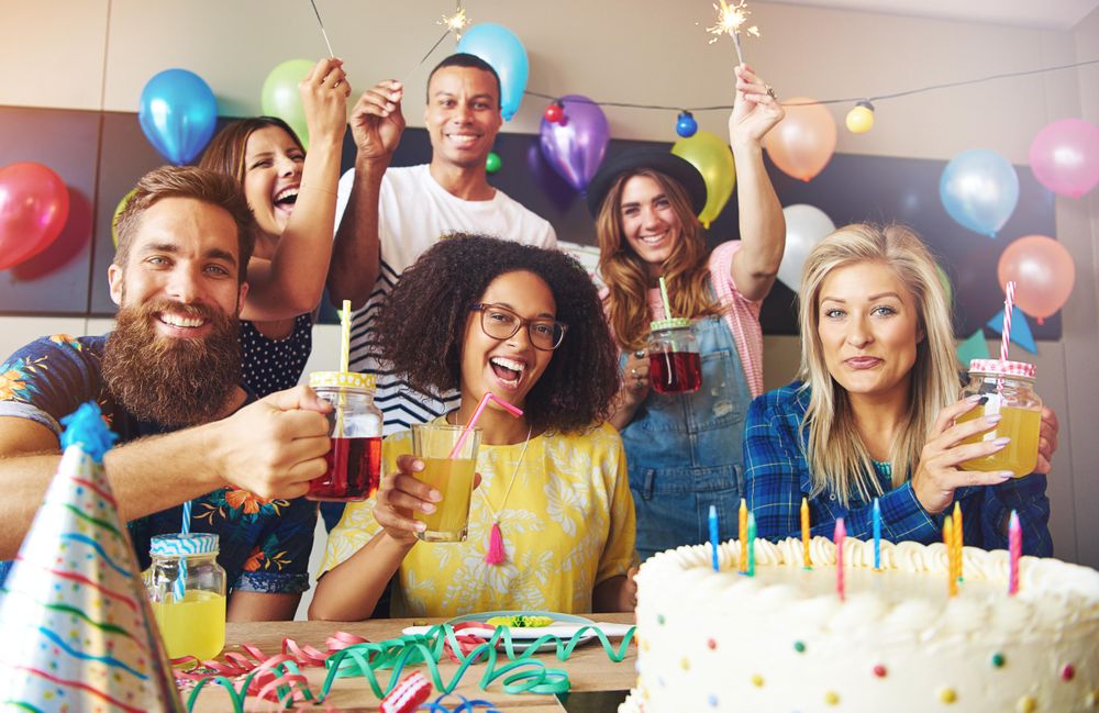Friends at birthday party with cake, balloons and sparklers