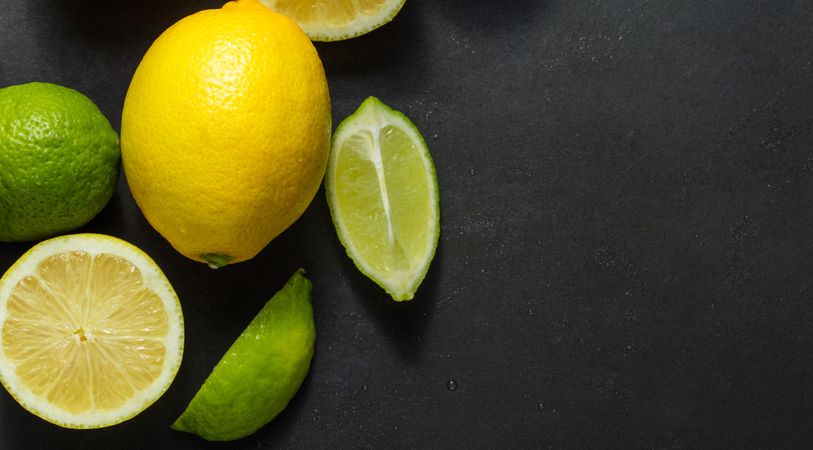 Cut and uncut limes and lemons on a dark background