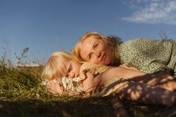 Mother and daughter lying on grassy ground in countryside