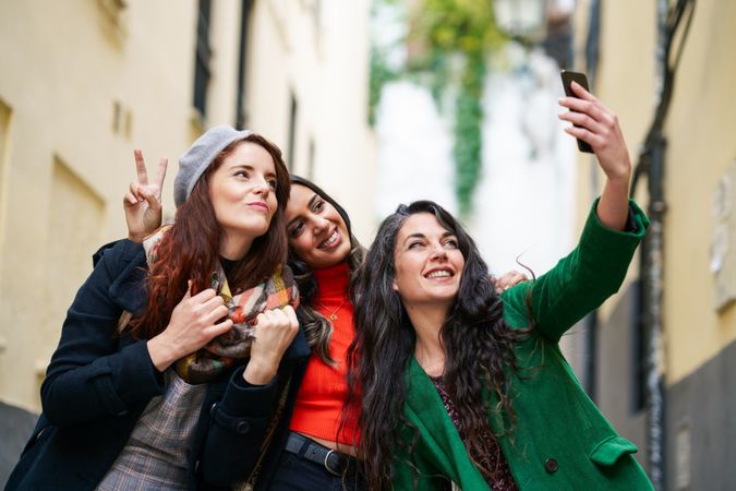 Three female friends dressed in fall clothes pose for selfie