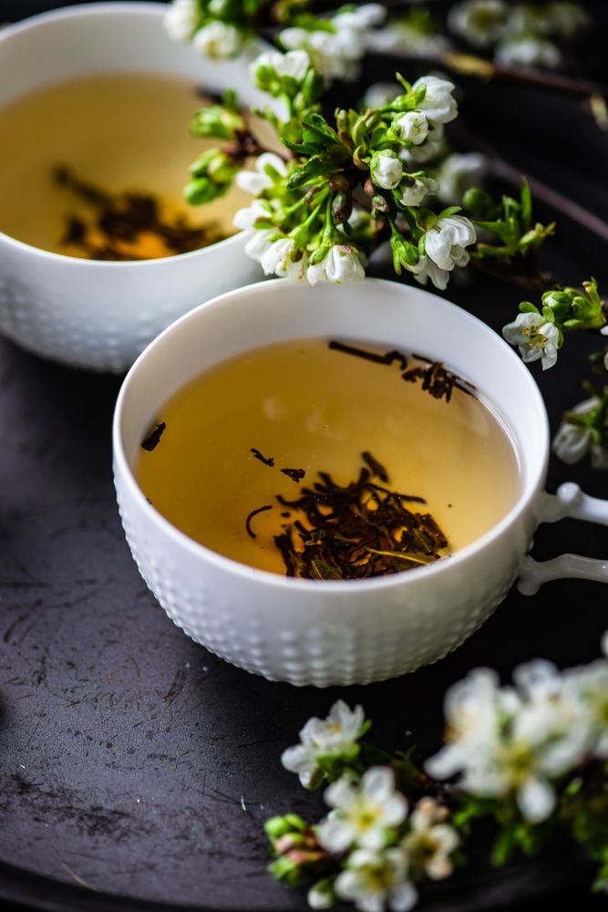 Green tea in cups with fragrant floral garnish