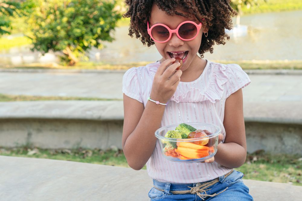 Girl eating vegan food during outdoor trip on summer vacation