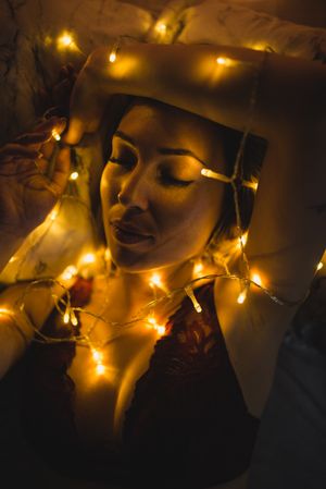 Woman lying surrounded by light garland