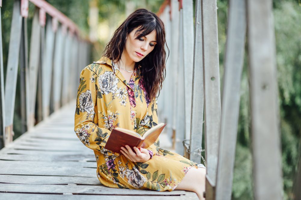 Female sitting on a rural bridge and reading